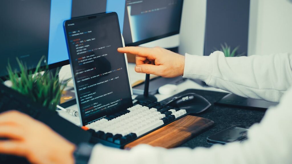 pexels photo 36496927 A programmer working on code with a laptop and monitor setup in an office.